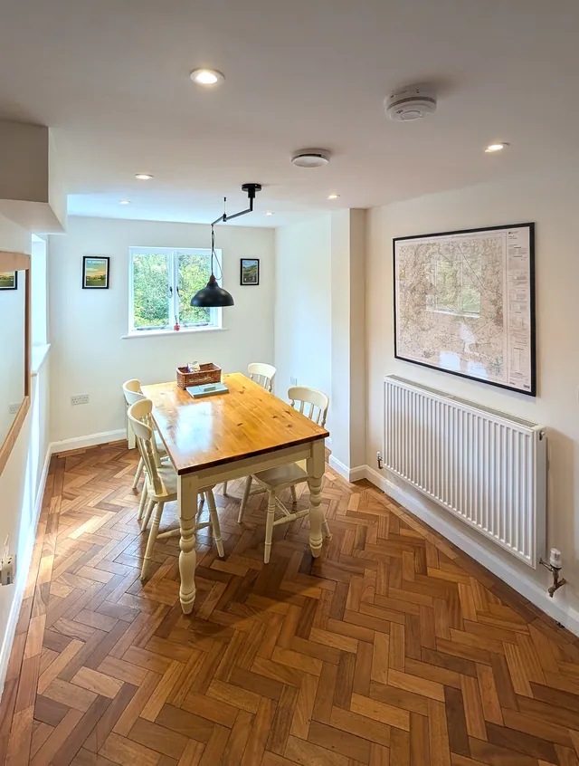 The dining table for four beneath a window, with a large framed map on the wall